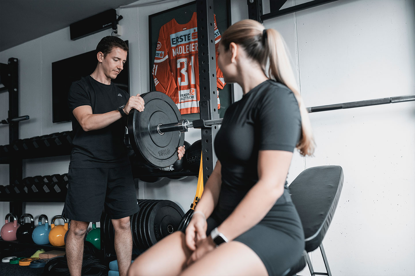 Trainer bringt das Gewicht an der Langhantelscheibe an